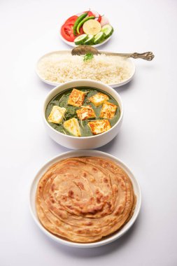 Palak paneer veya ıspanak ve süzme peynirli köri pilav ve chapati ile servis edilir.