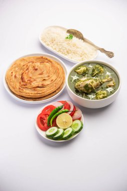 Yeşil Palak Köri Tavuğu veya Murgh Hariyali Tikka Masala veya Ispanak Murg Saagwala pirinç ve laccha paratha ile servis edilir.