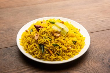 Köri yaprağı, fıstık ve kırmızı biberli limonlu pilav, seramik bir kasede servis ediliyor, seçici bir odak noktası.