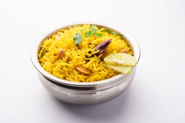 Köri yaprağı, fıstık ve kırmızı biberli limonlu pilav, seramik bir kasede servis ediliyor, seçici bir odak noktası.