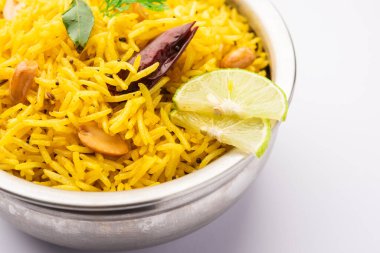 Köri yaprağı, fıstık ve kırmızı biberli limonlu pilav, seramik bir kasede servis ediliyor, seçici bir odak noktası.