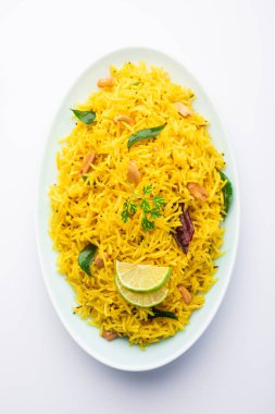 Köri yaprağı, fıstık ve kırmızı biberli limonlu pilav, seramik bir kasede servis ediliyor, seçici bir odak noktası.