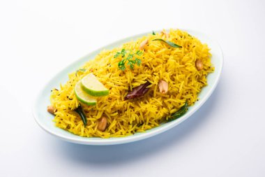 Köri yaprağı, fıstık ve kırmızı biberli limonlu pilav, seramik bir kasede servis ediliyor, seçici bir odak noktası.