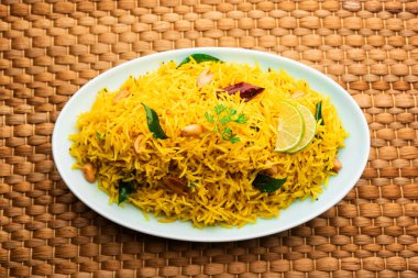 Köri yaprağı, fıstık ve kırmızı biberli limonlu pilav, seramik bir kasede servis ediliyor, seçici bir odak noktası.