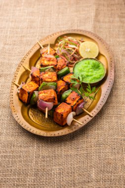 Paneer tikka is an Indian dish made from chunks of cottage cheese marinated in spices and grilled in a tandoor clipart