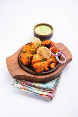 Hint tavuk tikka kebabı, baharat ve yoğurt ile marine edilmiş ve tandırda kızartılmış. Yeşil turşu ve soğanla servis edilir. seçici odak