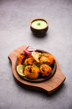 Hint tavuk tikka kebabı, baharat ve yoğurt ile marine edilmiş ve tandırda kızartılmış. Yeşil turşu ve soğanla servis edilir. seçici odak