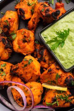 Hint tavuk tikka kebabı, baharat ve yoğurt ile marine edilmiş ve tandırda kızartılmış. Yeşil turşu ve soğanla servis edilir. seçici odak