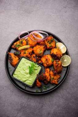 Hint tavuk tikka kebabı, baharat ve yoğurt ile marine edilmiş ve tandırda kızartılmış. Yeşil turşu ve soğanla servis edilir. seçici odak