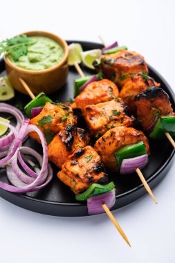 Hint tavuk tikka kebabı, baharat ve yoğurt ile marine edilmiş ve tandırda kızartılmış. Yeşil turşu ve soğanla servis edilir. seçici odak