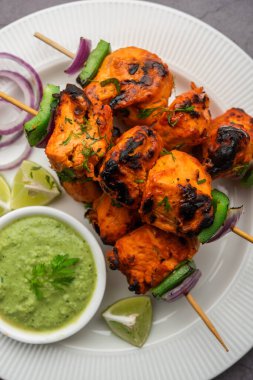 Hint tavuk tikka kebabı, baharat ve yoğurt ile marine edilmiş ve tandırda kızartılmış. Yeşil turşu ve soğanla servis edilir. seçici odak