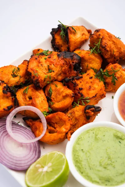 Hint tavuk tikka kebabı, baharat ve yoğurt ile marine edilmiş ve tandırda kızartılmış. Yeşil turşu ve soğanla servis edilir. seçici odak