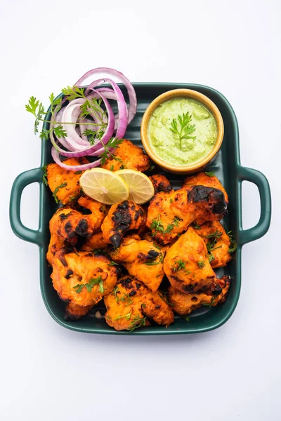 Hint tavuk tikka kebabı, baharat ve yoğurt ile marine edilmiş ve tandırda kızartılmış. Yeşil turşu ve soğanla servis edilir. seçici odak