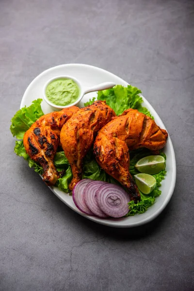 Tandoori chicken is a chicken dish prepared by roasting chicken marinated in yogurt and spices in a tandoor or a clay oven, served with onion and green chutney