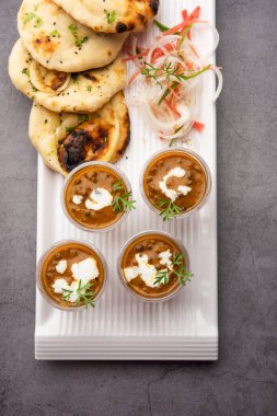 Dal Makhani veya dal Makhni Shots with Naan böbrek fasülyesi, tereyağı ve krema ve sarımsaklı naan veya Hint ekmeği veya roti ile servis edilir.