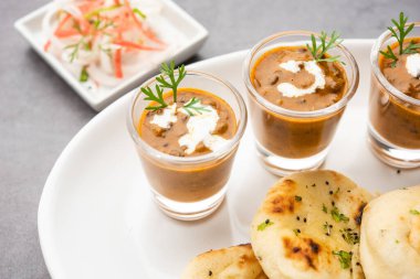 Dal Makhani veya dal Makhni Shots with Naan böbrek fasülyesi, tereyağı ve krema ve sarımsaklı naan veya Hint ekmeği veya roti ile servis edilir.