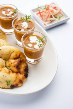 Dal Makhani veya dal Makhni Shots with Naan böbrek fasülyesi, tereyağı ve krema ve sarımsaklı naan veya Hint ekmeği veya roti ile servis edilir.