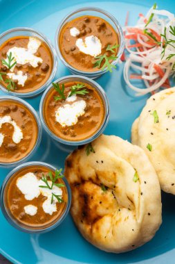 Dal Makhani veya dal Makhni Shots with Naan böbrek fasülyesi, tereyağı ve krema ve sarımsaklı naan veya Hint ekmeği veya roti ile servis edilir.