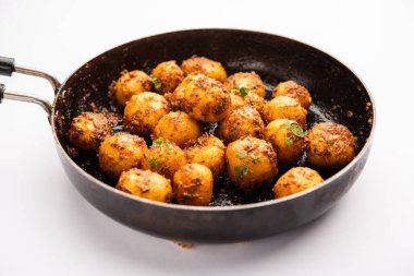 Ev yapımı Bombay patatesleri. Tavada kızartılmış küçük patates ya da jeera tohumlu aloo ve kase içinde kişniş.