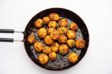 Ev yapımı Bombay patatesleri. Tavada kızartılmış küçük patates ya da jeera tohumlu aloo ve kase içinde kişniş.