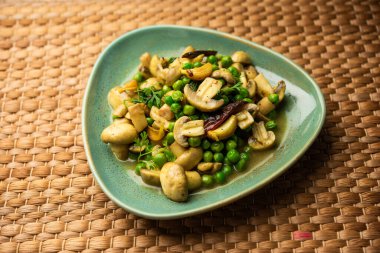 Kızarmış sarımsaklı mantar ve bezelye körisi, Hint yemeği kasede servis edilir.