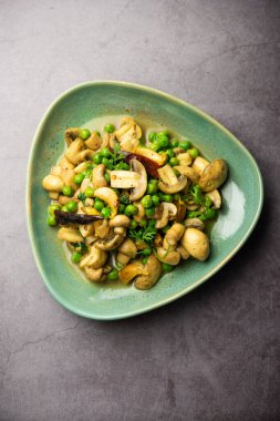 Kızarmış sarımsaklı mantar ve bezelye körisi, Hint yemeği kasede servis edilir.