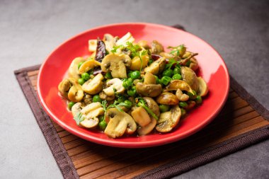 Kızarmış sarımsaklı mantar ve bezelye körisi, Hint yemeği kasede servis edilir.