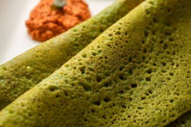 Palak dosa made using mixing spinach or keerai in batter, served with red chutney