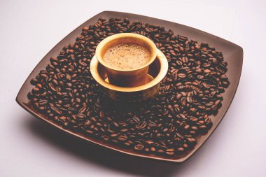 Geleneksel bir bardakta ya da kavrulmuş çiğ fasulyenin üzerinde servis edilen Güney Hindistan Filtresi kahvesi.