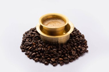 Geleneksel bir bardakta ya da kavrulmuş çiğ fasulyenin üzerinde servis edilen Güney Hindistan Filtresi kahvesi.