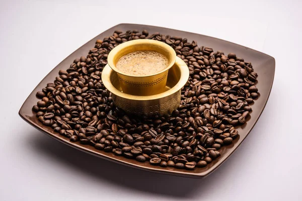 South Indian Filter coffee served in a traditional tumbler or cup over roasted raw beans