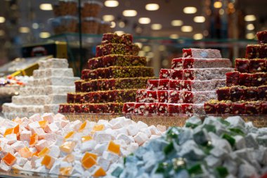 Sıra sıra Türk tatlıları, piramit şeklinde kurutulmuş meyvelerle çeşitlendiriliyor ve mağazanın vitrinine diziliyor