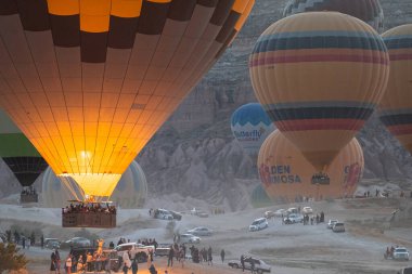 GOREME, TURKEY - 5 Ağustos 2021: Kapadokya Vadisi 'nde sıcak hava balonları havalanırken bir grup turist sabahları kutlama yapmak ve fotoğraf çekmek için toplanıyor