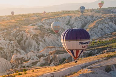 GOREME, TURKEY - 3 AĞUSTOS 2021: Kapadokya Vadisi üzerinde sabah vakti yere çok yakın uçan turistlerle dolu renkli sıcak hava balonuna yakın çekim