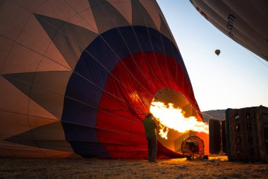 GOREME, TURKEY - 3 AĞUSTOS 2021: İnsanlar sıcak hava balonunu ocaktaki sıcak havayı kullanarak yerde şişirmek için çok çalışıyorlar.