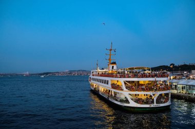 ISTANBUL, TURKEY - 10 Ağustos 2021: Büyük feribot turist ve yerlilerle birlikte İstanbul Boğazı 'ndaki Karaköy feribot terminalinden ayrılmaya hazırlanıyor ve gün batımında Golden Horn' da geziniyorlar.