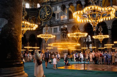 İSTANBUL, TURKEY - 9 AĞUSTOS 2021: Sultanahmet ilçesindeki Ayasofya Camii 'nin içi turistler ve güzel avizelerle dolu
