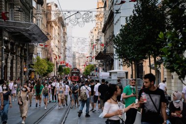 İSTANBUL, TURKEY - 18 Temmuz 2021: İkonik Taksim Tüneli Nostalji kırmızı tramvayı Taksim Meydanı yolunda yürüyen insanların yanından geçiyor