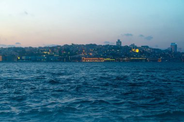 İstanbul şehrinin günbatımı manzarası Altın Boynuz üzerinde ufuk çizgisi ve ön planda Boğaz dalgaları