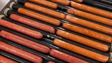 top view closeup of hotdog sausages getting fried on a rolling hot grill