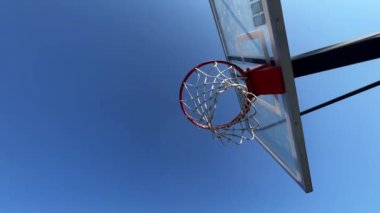 Açık hava basketbol sepetinin yakın plan görüntüsü. Altından mavi gökyüzüne doğru beyaz halat manzaralı. 