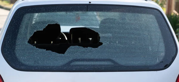 closeup of broken rear windshield glass on the back of a car with no people