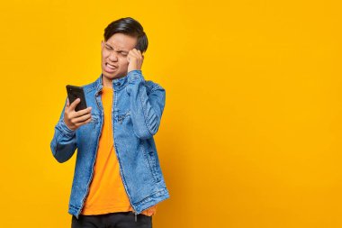 Şok olmuş Asyalı genç adam akıllı telefondan mesaja bakıyor.