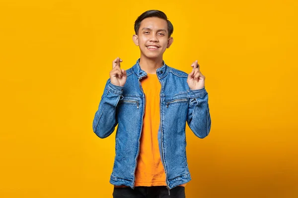 笑顔若いアジアの男の肖像制服ジェスチャー指交差上の黄色の背景 — ストック写真