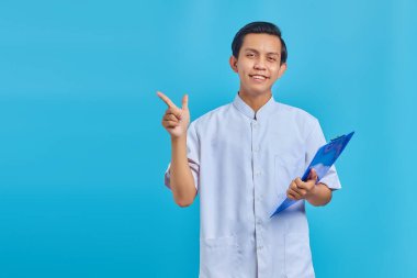 Mavi arka planda duran ve boş alanı gösteren neşeli erkek hemşire.