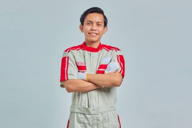 Genç Asyalı tamirci gri arka plandaki kameraya gülümsüyor.