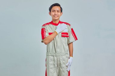 Genç tamircinin portresi Gri arka planda izole edilmiş yüzünde büyük bir gülümsemeyle selamlıyor.