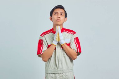 Yakışıklı genç tamircinin portresi. Elleriyle yalvarıyor ve dua ediyor. Çok duygusal ve endişeli bir yüz ifadesiyle.