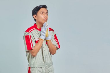 Yakışıklı genç tamircinin portresi. Elleriyle yalvarıyor ve dua ediyor. Çok duygusal ve endişeli bir yüz ifadesiyle.