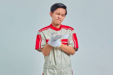 Mekanik üniforma giyen yakışıklı bir adamın portresi. Gri arka planda ellerde ve parmaklarda acıdan muzdarip.